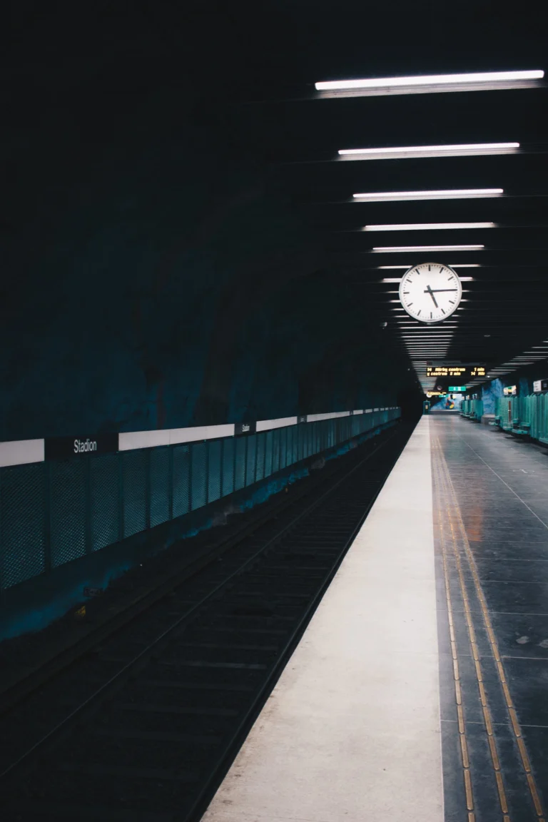 Verlaten perron van metrostation Stadion in Stockholm, met tl-balken aan het plafond en een grote klok op de achtergrond. Een metafoor voor wachten en tijdsdruk: wat doe je als de dienst waar je van afhankelijk bent er opeens niet meer is?